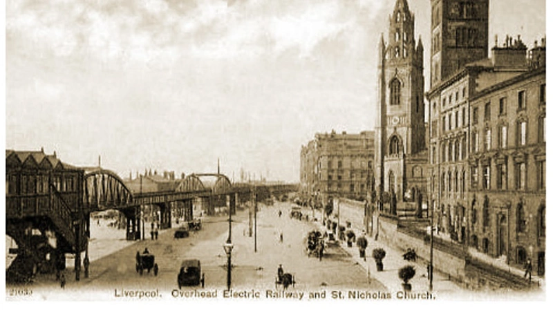 Sepia postcard of the Liverpool Overhead Railway on its elevated track beside the dock road, with St Nicholas Church to the right